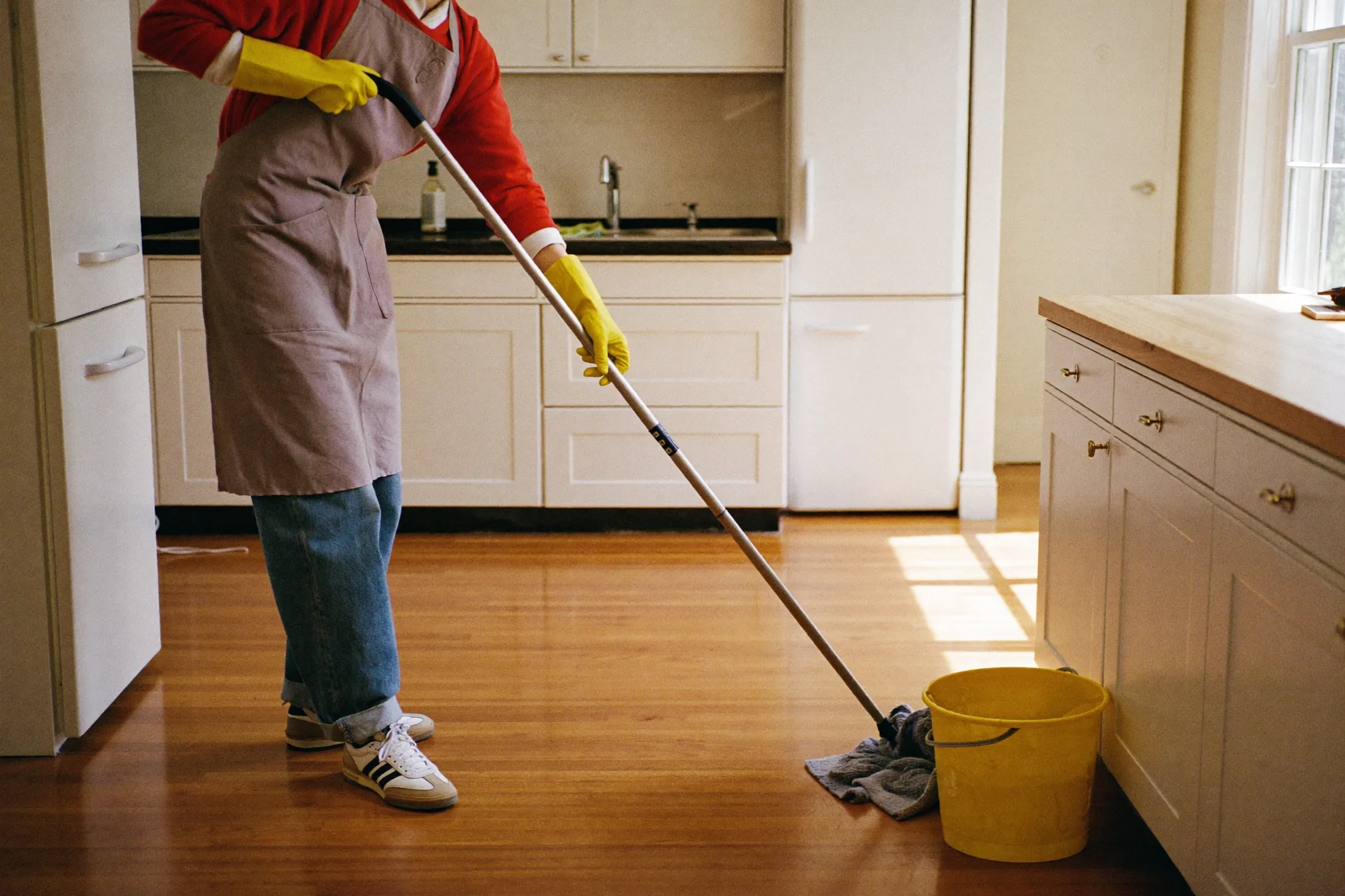 A cleaner wiping a kitchen countertop with a spray bottle and cloth
